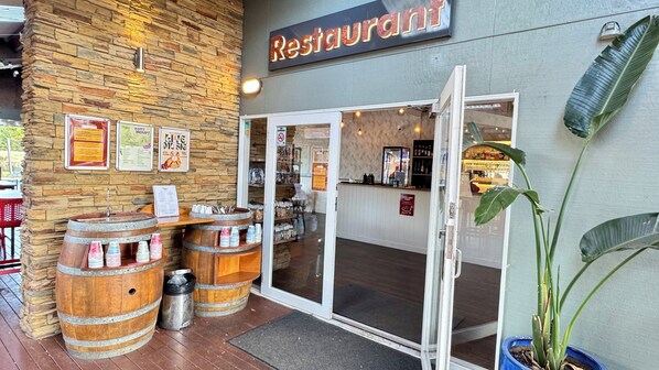A restaurant with a stone facade, wooden barrels, and a glass door entrance.