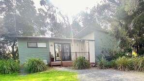 Einbungalow mit einer Veranda, einem kleinen Hauseingang und einer sichtbaren Garagentür.