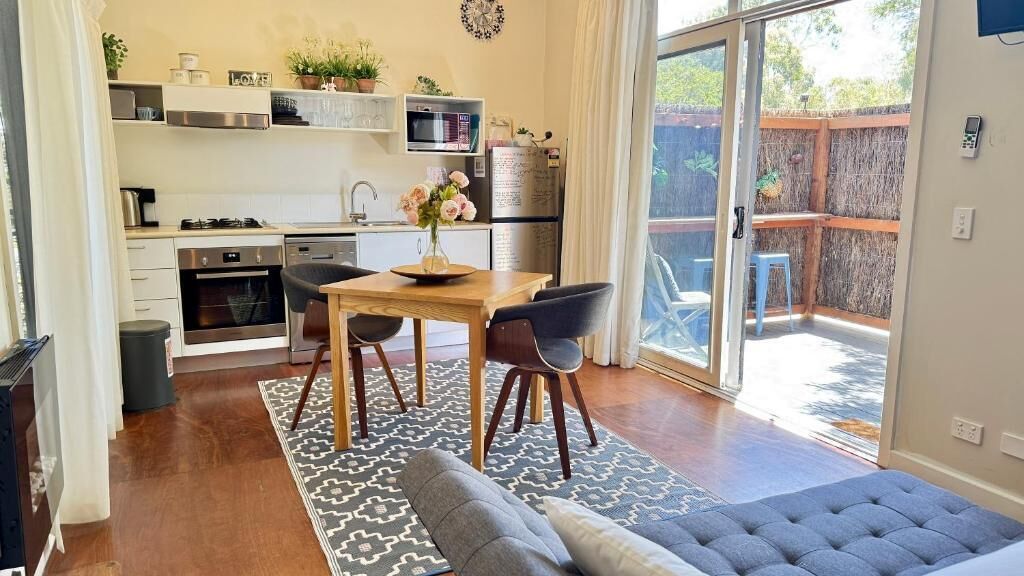 Eine moderne Küche mit Essbereich, einer Couch und Blick ins Freie.