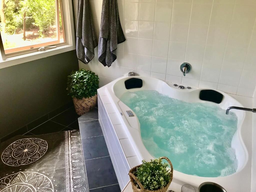 Un baño con bañera, una ventana con cortinas y una planta en maceta.