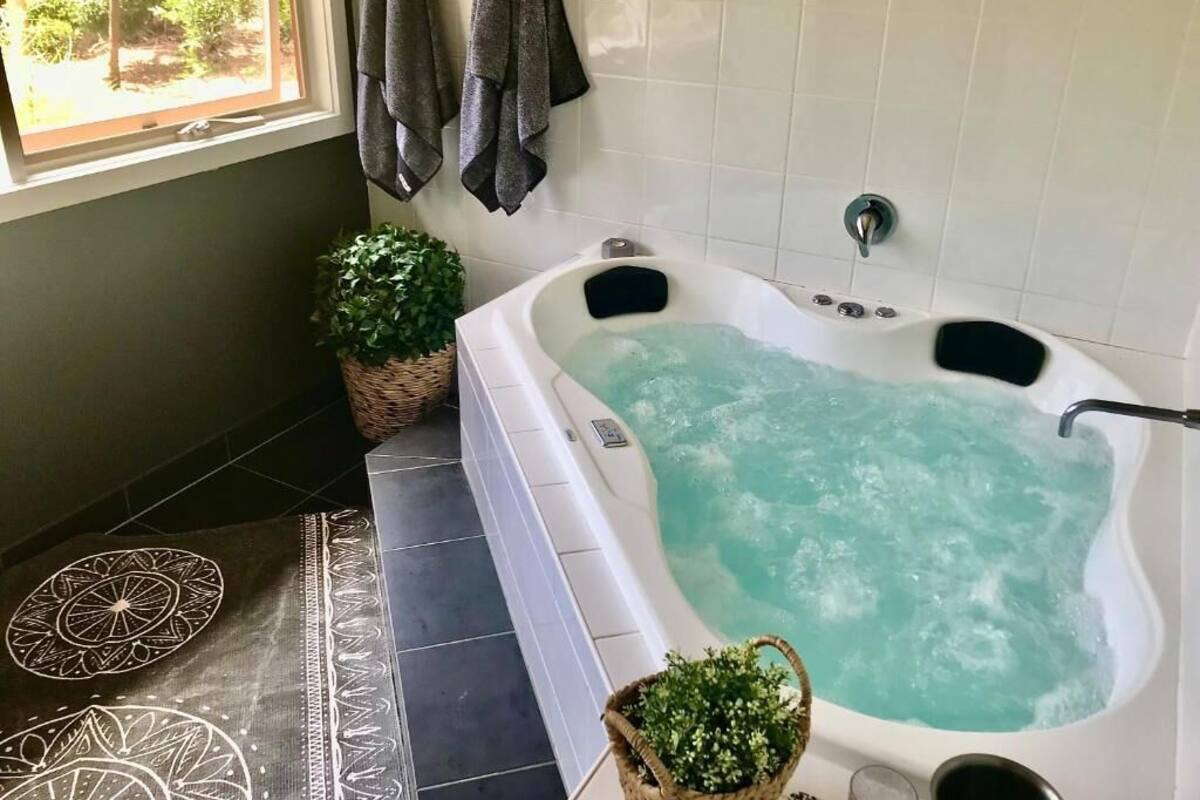 Un baño con bañera, una ventana con cortinas y una planta en maceta.