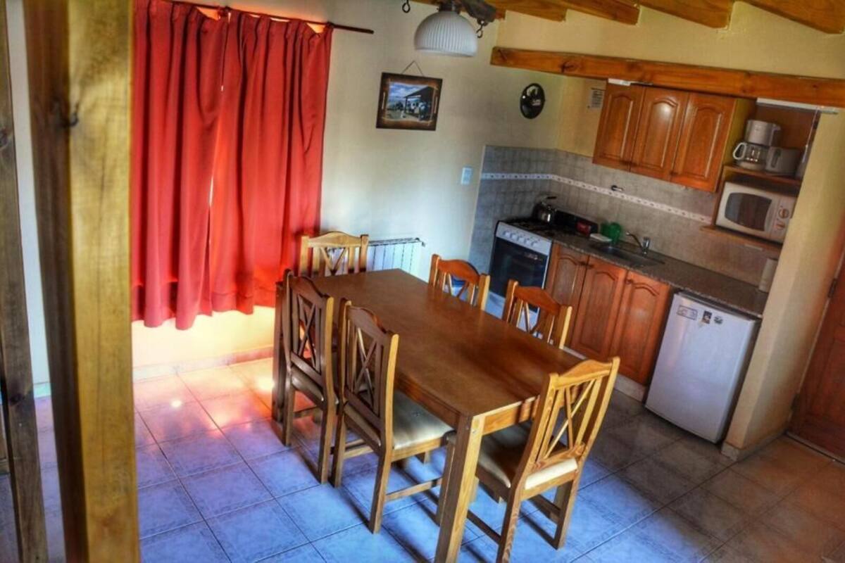 A compact kitchen with wooden cabinets, a built-in oven, a microwave, and a small refrigerator.