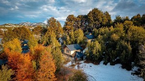 A residential area with houses surrounded by trees and a snowy landscape. - Complejo Moquehue (Villa Pehuenia)