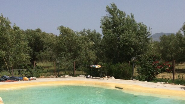 A clear pool with a sandy edge, surrounded by trees and a clear sky. - Casa Raffaello, just a stone's throw from the sea. Complete relaxation and tranquility. (Sicilia)