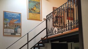 A staircase with a wrought iron railing, a green sofa, and various framed artworks on the walls. - Casa Raffaello, just a stone's throw from the sea. Complete relaxation and tranquility. (Sicilia)