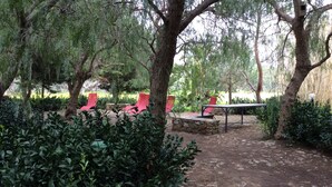 A garden with a stone fire pit, red chairs, and a table. - Casa Raffaello, just a stone's throw from the sea. Complete relaxation and tranquility. (Sicilia)