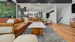 Ein modernes Wohnzimmer mit einer Eckcouch, einem Couchtisch und einem Fernseher.