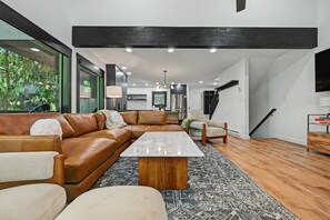 A modern living room with a sectional sofa, a coffee table, and a TV. - Designer Ski In/Out Retreat | Pool, Spa & More (Tannersville)