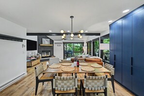 A modern dining area with a wooden table, woven placemats, and a ceiling fan. - Designer Ski In/Out Retreat | Pool, Spa & More (Tannersville)