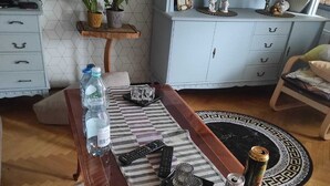 A dining table with remote controls, a water bottle, a can, and decorative items.