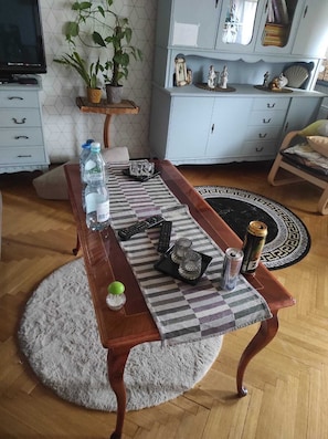 Una mesa de comedor con controles remotos, una botella de agua, una lata y objetos decorativos.