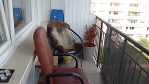 A balcony with a chair, a small table with a tray, and a window.