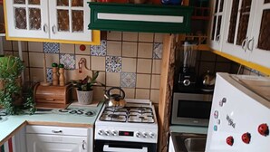 A compact kitchen with white cabinets, a gas stove, an oven, and a refrigerator.