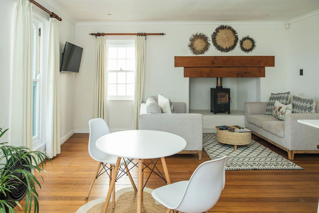 A living room with a fireplace, a television, a round table with chairs, and a sofa with patterned cushions.