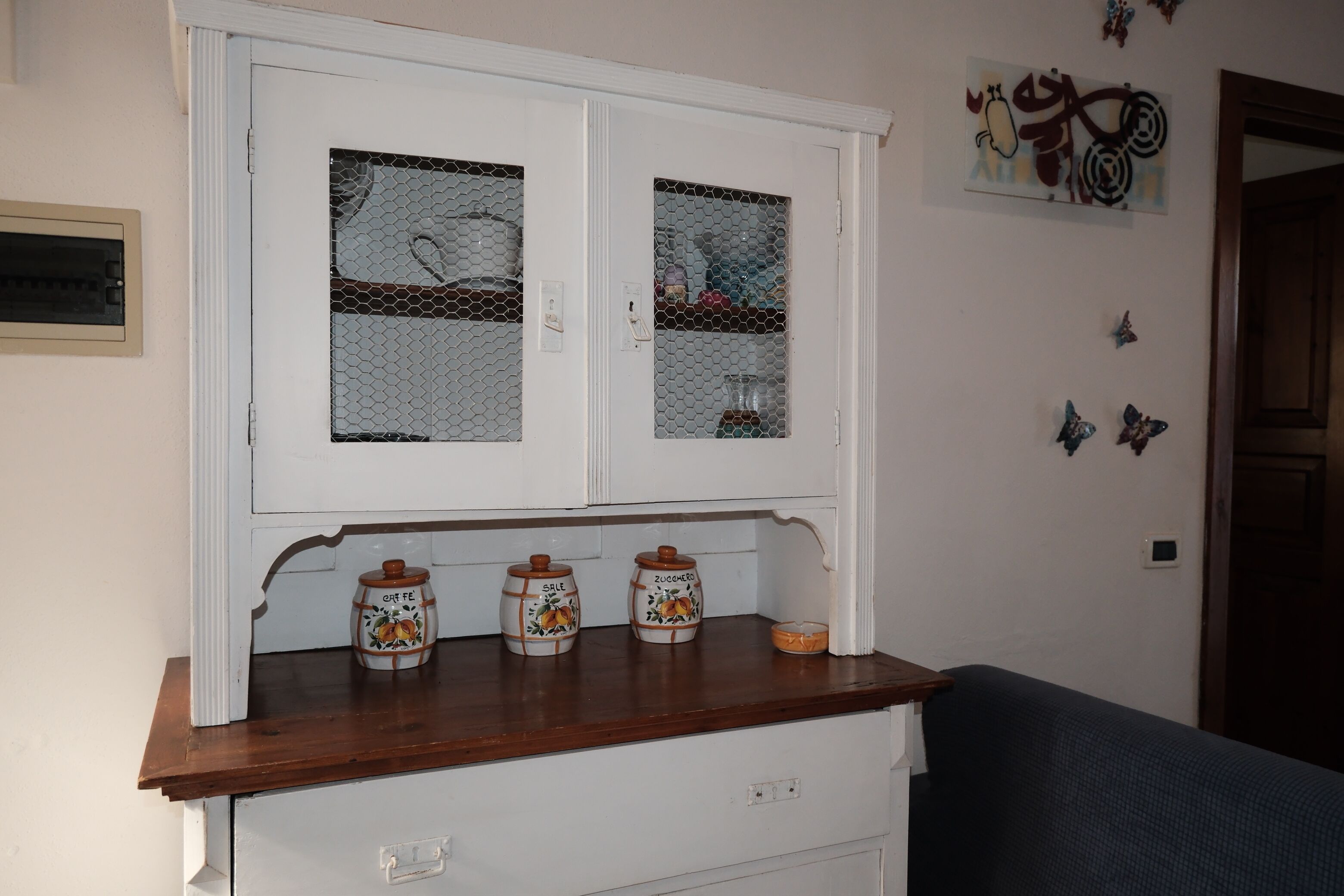 Un meuble blanc avec deux portes en verre, un plan de travail en bois et des ustensiles de cuisine.