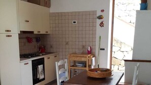 Eine Küche mit Esstisch, Stühlen, Schränken, einem Herd und einer Hängelampe.