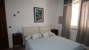 Ein Schlafzimmer mit einem Bett, einem Nachttisch, einer Wanduhr und einem gerahmten Bild.