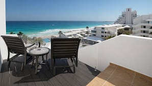 A balcony with two chairs and a table overlooking a beach and ocean. - Large Group Getaway - Brisas Cancun Condo 3401 (Cancún)