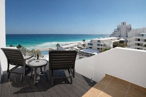A balcony with two chairs and a table overlooking a beach and ocean. - Large Group Getaway - Brisas Cancun Condo 3401 (Cancún)