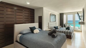 A hotel room with a large bed, a smaller bed, a TV, a view of the ocean, and a balcony. - Large Group Getaway - Brisas Cancun Condo 3401 (Cancún)
