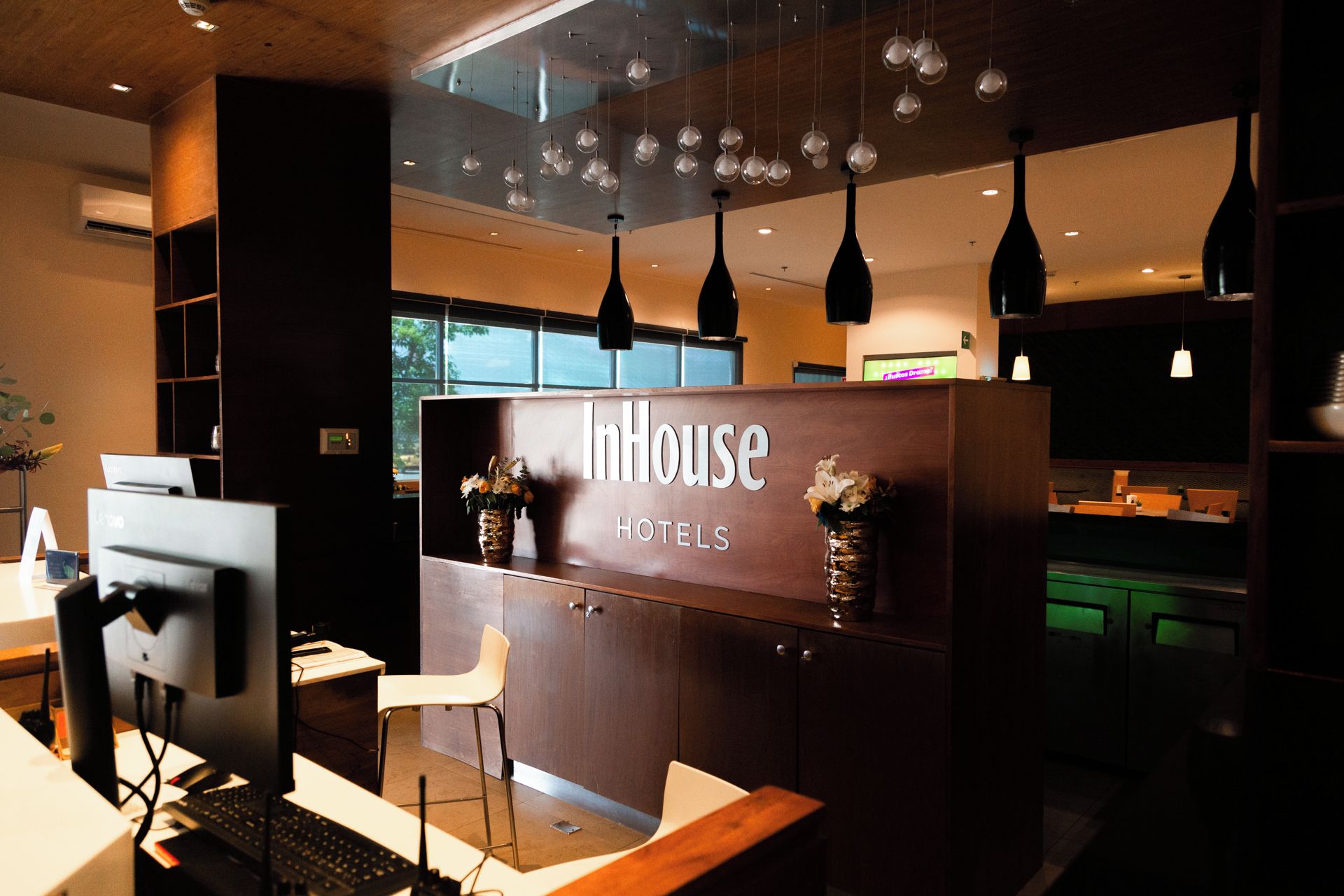 A reception desk with a sign reading 'InnHouse Hotels' and a modern interior design with pendant lighting.