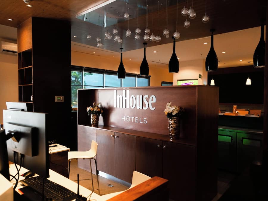 Una recepción con un letrero que dice 'InnHouse Hotels' y un diseño de interiores moderno con iluminación colgante.