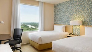 Une chambre d’hôtel avec deux lits, un bureau, une chaise et une vue sur une rivière.