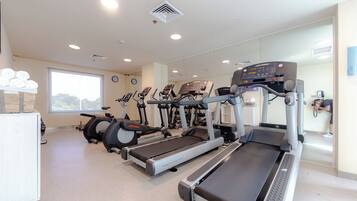 A gym with treadmills, stationary bikes, and a rowing machine.