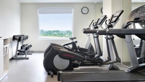 Une salle de sport équipée de tapis de course, d’un appareil elliptique et d’un banc de musculation.