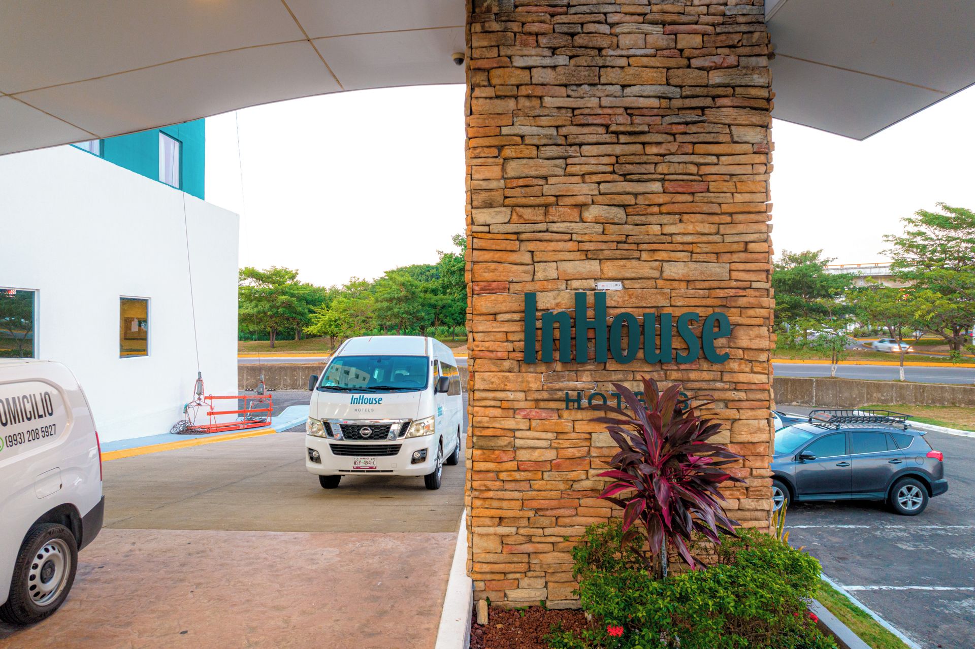 A hotel entrance with a stone pillar displaying the name 'InHouse Hotel'.