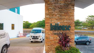 A hotel entrance with a stone pillar displaying the name 'InHouse Hotel'.