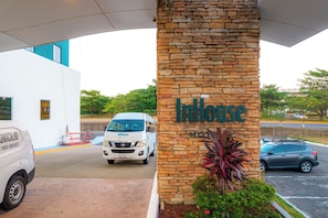Fachada de un hotel con un pilar de piedra que muestra el nombre 'InHouse Hotel'.