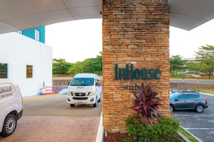 Fachada de un hotel con un pilar de piedra que muestra el nombre 'InHouse Hotel'.