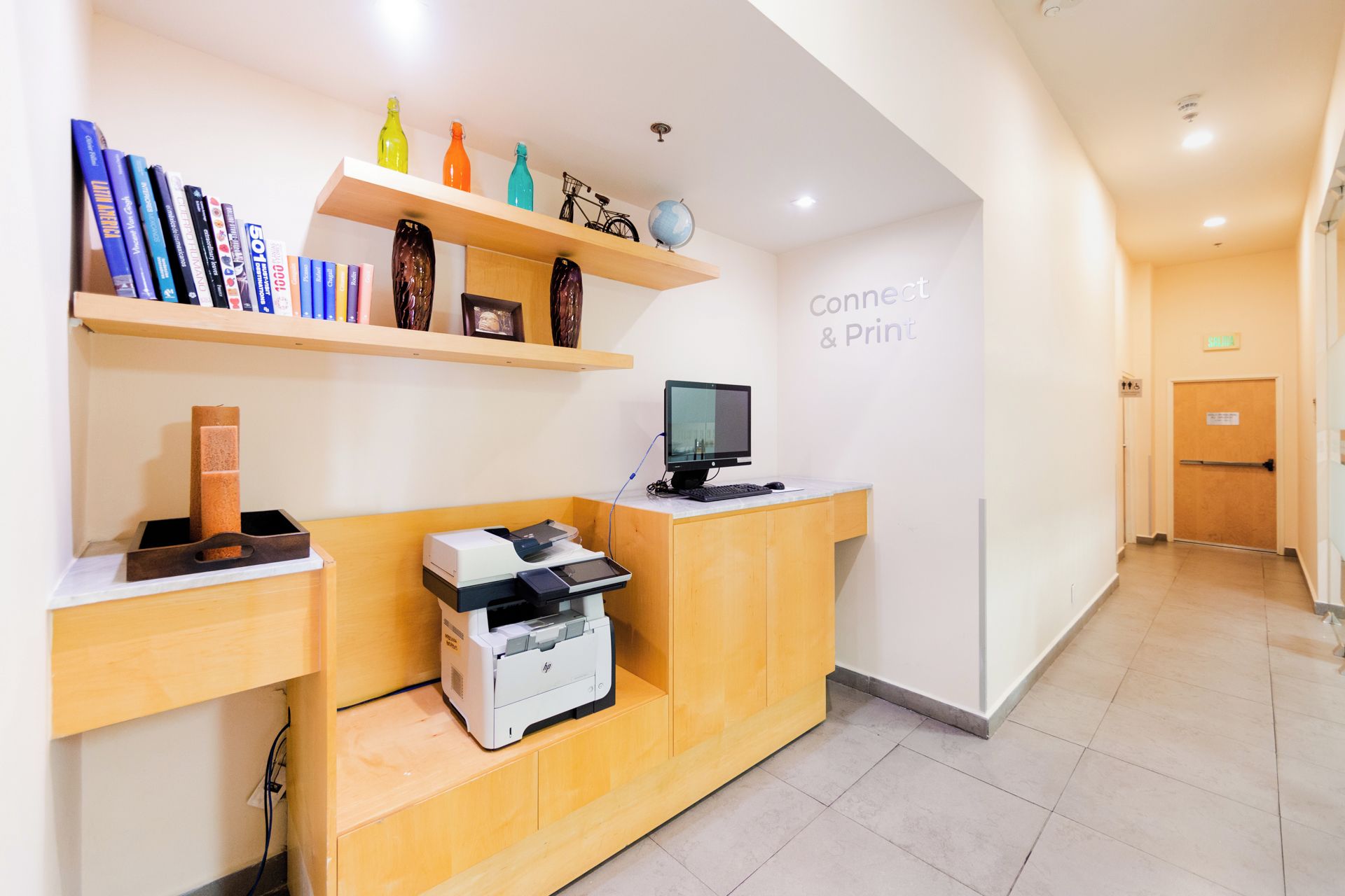A reception desk with a computer monitor, printer, and bookshelves.