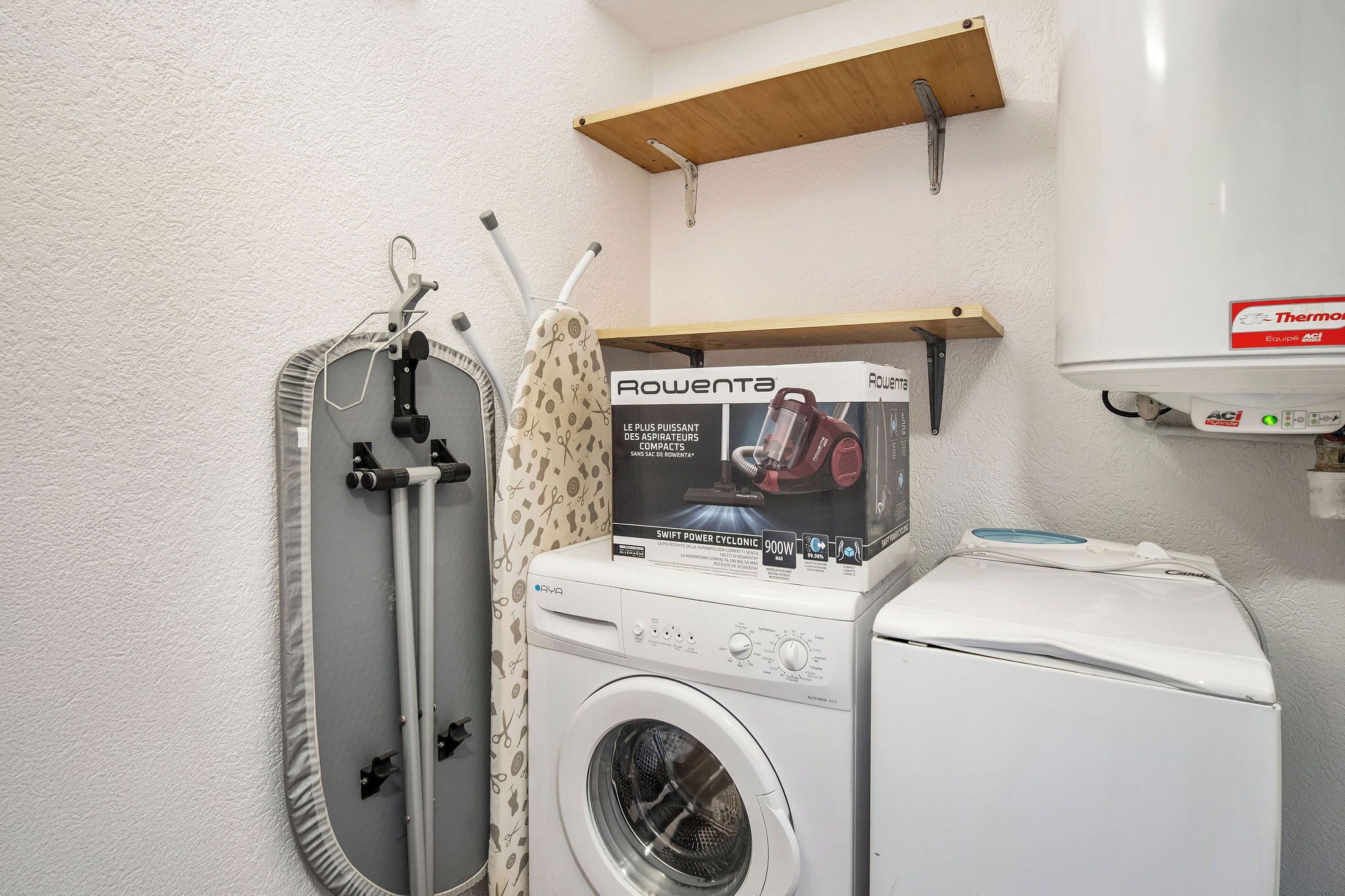 Ein Waschraum mit Waschmaschine, Trockner und einer Wandtrocknervorrichtung.