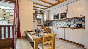 A kitchen with a dining table, chairs, a microwave, and patterned backsplash. - La Reine Blanche  (Les Belleville)