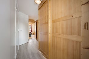 A hallway with wooden doors, a white door, and a ceiling light. - La Reine Blanche  (Les Belleville)