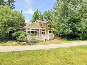 A two-story house with a covered porch and a front yard.