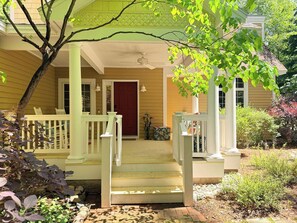 A house with a porch, a red door, and a staircase leading to the entrance.