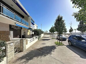 Ein Wohngebäude mit blauem Vordach, einem verschlossenen Eingangsbereich und einem gepflasterten Auffahrt.