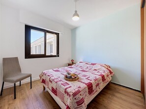 Une chambre à coucher avec un lit, une chaise, une fenêtre et un luminaire suspendu.