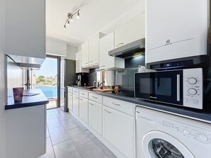 A modern kitchen with white cabinets, a built-in oven, microwave, and dishwasher. - Aigo Sau 3 by Interhome (Le Grau du Roi)
