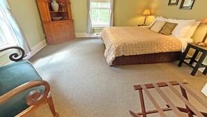 A bedroom with a bed, a chair, a wooden cabinet, a window, and a lamp. - Oceanfront Suite with Private Deck & Ensuite Bath - Rm 11 (Gabriola)
