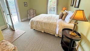 A bedroom with a bed, a chair, a lamp, a window, and a door. - Oceanfront Suite with Private Deck & Ensuite Bath - Rm 11 (Gabriola)