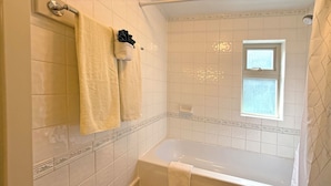A bathroom with a bathtub, a window, and two towels hanging on a rack. - Oceanfront Suite with Private Deck & Ensuite Bath - Rm 11 (Gabriola)