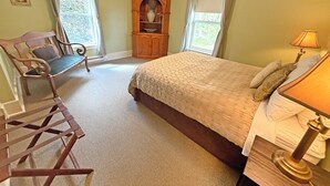 A bedroom with a bed, a chair, a wooden cabinet, and a lamp. - Oceanfront Suite with Private Deck & Ensuite Bath - Rm 11 (Gabriola)