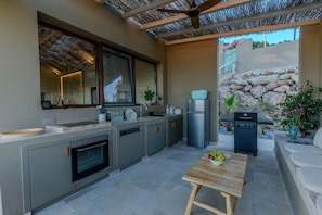 A modern kitchen with a built-in oven, a sink, and a refrigerator. There is a wooden table with fruit on it. - Romantic Private Pool Villa with Spectacular 180° Ocean Views (Korissia)