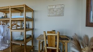 Een houten stoel en tafel in een kamer met een wandplank en een ingelijste foto.