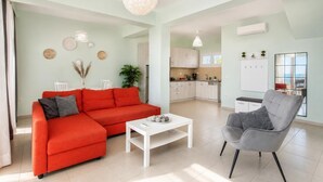 Ein modernes Wohnzimmer mit einem roten Sofa, einem weißen Couchtisch und einem grauen Sessel.