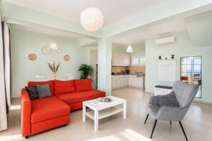 Een moderne woonkamer met een rode bank, een witte salontafel en een grijze fauteuil.